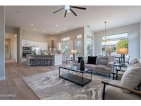 Bright, open-concept living room featuring modern decor, hardwood floors, and natural light at 19608 N Regents Park Dr, Surprise, AZ 85387