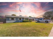 Charming single-story home with a well-maintained lawn, an American flag, and a classic pickup truck parked in the driveway at 2145 W Cholla St, Phoenix, AZ 85029