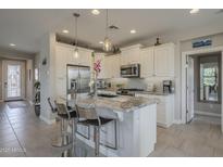 Bright kitchen features stainless steel appliances, granite countertops, pendant lighting, and tiled floors at 36042 N Desert Tea Dr, Queen Creek, AZ 85140