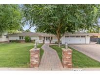 Charming home with a brick pathway, lush lawn, mature trees, and a classic white picket fence at 3817 E Highland Ave, Phoenix, AZ 85018