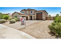 Two-story home featuring three-car garage, desert landscaping, and concrete driveway at 44157 W Palo Amarillo Rd, Maricopa, AZ 85138