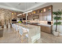 Luxurious kitchen with a stone accent wall, an oversized island, and stainless steel appliances at 12311 E Black Rock Rd, Scottsdale, AZ 85255