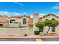 Inviting beige condo with a vibrant orange tiled roof, lush green tree, and well-maintained front yard under a clear blue sky at 1717 E Union Hills Dr # 1033, Phoenix, AZ 85024