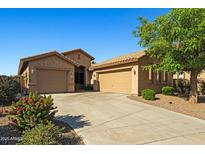 Inviting single-story home featuring a three-car garage, desert landscaping, and a charming facade under a clear blue sky at 15422 W Ventura St, Surprise, AZ 85379