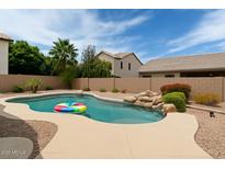 Backyard pool with rock feature, patio, and mature landscaping at 2834 E Devon Ct, Gilbert, AZ 85296