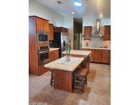 A kitchen with stainless steel appliances, brown cabinets, a kitchen island, and neutral tile flooring at 9302 E Broadway Rd # 157, Mesa, AZ 85208