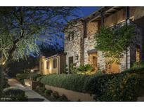 Inviting stone-clad home with manicured landscaping and warm exterior lighting at twilight at 10287 E Diamond Rim Dr, Scottsdale, AZ 85255