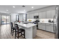 Stylish kitchen features modern cabinets, quartz countertops, stainless appliances, island with seating at 11574 W Luxton Ln, Avondale, AZ 85323