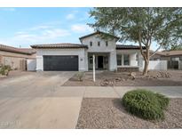 Charming single-story home with a well-manicured front yard and a black two car garage door at 20823 S 185Th Way, Queen Creek, AZ 85142