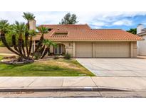 Charming two-story home features a red tile roof, three-car garage and mature palm trees at 3337 E Glade Cir, Mesa, AZ 85204