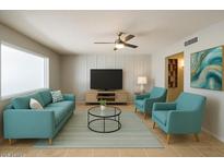 Bright living room with stylish teal furniture, ceiling fan, and large window at 5342 E Des Moines St, Mesa, AZ 85205
