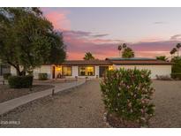 Charming single-story home featuring a lush, landscaped yard and inviting walkway under a beautiful sunset sky at 12866 W Orange Dr, Litchfield Park, AZ 85340