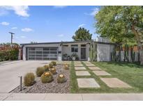 Contemporary home featuring desert landscaping, a unique paver walkway and a glass garage door at 3402 E Sells Dr, Phoenix, AZ 85018