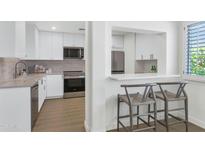 Modern kitchen with stainless steel appliances and white cabinets with bar stool seating at 4201 E Camelback Rd # 70, Phoenix, AZ 85018