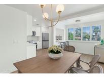 Bright open kitchen featuring stainless steel appliances, white cabinets, and wood flooring extending to the dining area at 4201 E Camelback Rd # 70, Phoenix, AZ 85018