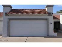 Attached two-car garage featuring a red tile roof and a white door at 4718 W Sanna St, Glendale, AZ 85302