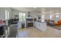 Open kitchen featuring stainless steel appliances, white cabinets, black counters, and light wood flooring at 520 S Macdonald --, Mesa, AZ 85210