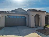 Charming single-story home with a tile roof, arched entry, and two-car garage under a bright blue sky at 9137 W Sells Dr, Phoenix, AZ 85037