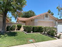 Charming single-story home featuring a tile roof, well-manicured lawn, and lush green shrubbery at 1020 W Sunward Dr, Gilbert, AZ 85233