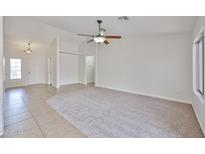 Bright living room featuring neutral tones, tile and carpet flooring, and a ceiling fan at 11626 W Holly St, Avondale, AZ 85392