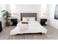 Beautifully staged bedroom featuring a plush bed, neutral tones, and ample natural light from two bright windows at 5928 S Daisy Patch Pl, Phoenix, AZ 85040