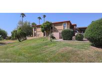 Inviting condo with lush green lawn and mature palm trees set against a clear blue sky at 10410 N Cave Creek Rd # 2220, Phoenix, AZ 85020