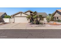Charming single-story home featuring a two-car garage, desert landscaping, and mature palm trees at 19930 N 98Th Ave, Peoria, AZ 85382