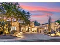 Stunning home with a desert landscape, warm lighting, and a beautiful sunset in the background at 21240 N 74Th Pl, Scottsdale, AZ 85255