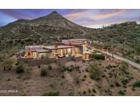 Stunning desert home with mountain backdrop, featuring an open design, outdoor fireplace, and desert landscaping at 39602 N Charles Blair Macdonald Rd, Scottsdale, AZ 85262