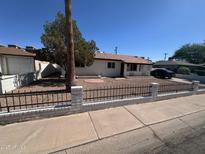Charming single-story home featuring a well-maintained front yard with decorative rock and black iron fence at 1408 E Orange St, Tempe, AZ 85281