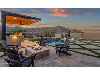 Inviting backyard with a modern pool, spa, outdoor kitchen, fire pit, and mountain views at 21632 W Hillcrest Blvd, Buckeye, AZ 85396