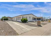 Charming single-story home features a white exterior, low maintenance landscaping, and covered carport at 2241 N Nicklaus Dr, Mesa, AZ 85215