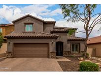 Two story home with a brick driveway, desert landscaping, and a brown tile roof at 26391 N 107Th Dr, Peoria, AZ 85383