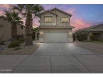 Inviting two-story home featuring a neutral color palette, a two car garage, and mature palm trees at 4041 W Hackamore Dr, Phoenix, AZ 85083