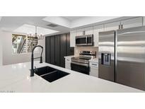 Modern kitchen featuring stainless steel appliances, white cabinets, and a large quartz countertop island with a black sink and faucet at 520 N Stapley Dr # 166, Mesa, AZ 85203