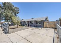 Charming single-story home featuring a gray exterior, spacious driveway, and secure fenced front yard at 7135 W Flower St, Phoenix, AZ 85033