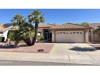 Charming single-story home featuring a well-manicured yard, tile roof, and a two-car garage at 9130 W Utopia Rd, Peoria, AZ 85382