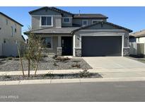Two-story home with gray stucco, stone accents, gray garage door and desert landscaping at 12816 N 172Nd Dr, Surprise, AZ 85388