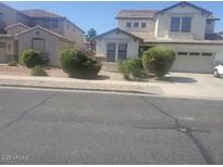 View of a charming two-story home with a well-manicured lawn and an attached two-car garage at 14150 W Boca Raton Rd, Surprise, AZ 85379