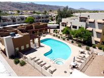 Aerial view of a community pool with lounge chairs, lush landscaping, and beautiful mountain views at 3434 E Baseline Rd # 214, Phoenix, AZ 85042