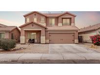 Two-story home boasts a two-car garage, a cozy front porch and low-maintenance landscaping at 45574 W Tulip Ln, Maricopa, AZ 85139