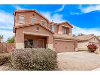 Two-story home boasts a two-car garage, a cozy front porch and colorful flowering bushes at 45574 W Tulip Ln, Maricopa, AZ 85139