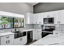 Renovated kitchen featuring a stainless steel dishwasher, subway tile backsplash, and quartz countertops at 8913 S Forest Ave, Tempe, AZ 85284