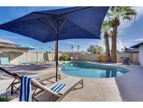 Inviting backyard pool area featuring lounge chairs, shade umbrella, and lush palm trees perfect for relaxation at 1142 E Westchester Dr, Tempe, AZ 85283