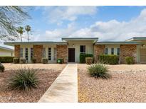 Charming single-story home with a well-maintained front yard and stone accents under a bright blue sky at 13428 N 100Th Ave, Sun City, AZ 85351