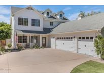 Elegant white home featuring a large driveway, three-car garage, manicured lawn, and a charming front porch at 7348 N 9Th Pl, Phoenix, AZ 85020