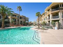 Beautiful pool with turquoise water, lounge chairs, and palm trees surrounded by multi-story apartment buildings on a sunny day at 7601 E Indian Bend Rd # 3030, Scottsdale, AZ 85250