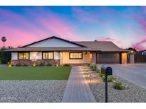 Charming single-story home with a well-manicured lawn and lovely curb appeal at dusk at 9005 W Villa Chula St, Peoria, AZ 85383