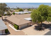 A high angle view of the exterior showing the roof, two-car garage, and nearby trees and community at 12831 W Maplewood Dr, Sun City West, AZ 85375