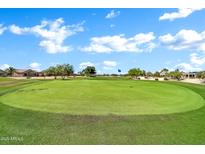 Picturesque golf course with vibrant green grass, a blue flag marking the hole, and homes in the distance at 15534 W Big Sky Dr, Surprise, AZ 85374